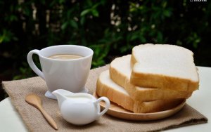 Tasse de café avec du lait et des tartines de pain