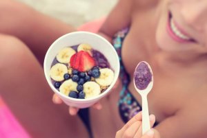 Une femme qui mange un bol de fruits.
