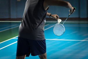 Un homme qui joue au badminton, l'un des sports de raquette les plus connus.