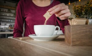 Une femme met du sucre dans son café