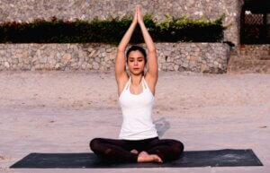 Femme en position indienne sur un tapis de yoga.