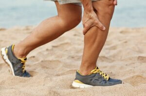 Un homme qui a une crampe au mollet.