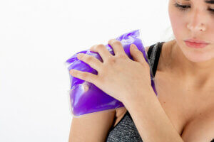 Une femme qui applique du froid sur son épaule.