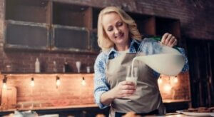 Une femme qui verse un verre de lait.
