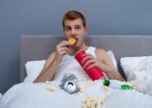 Un homme mangeant de la malbouffe dans son lit.