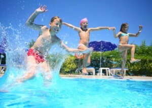 Trois enfants qui sautent dans une piscine.